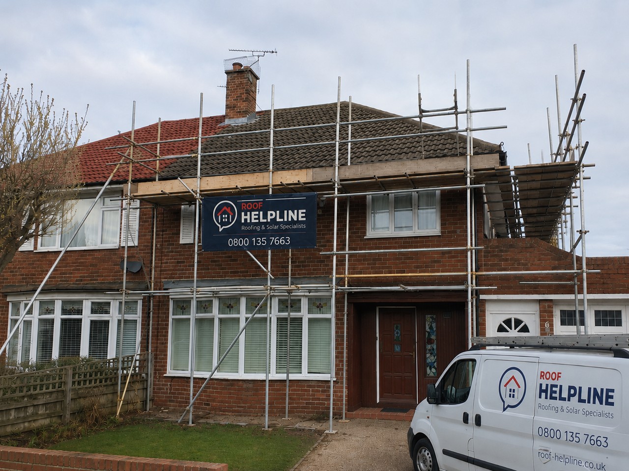 Scaffold tower erected against a house roof for a Roof Helpline job, with a branded site banner and van in the driveway